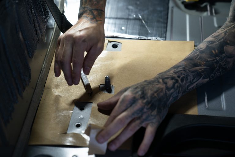 Someone in a Ford Bronco installing ResoNix Sound Solutions sound deadener close up